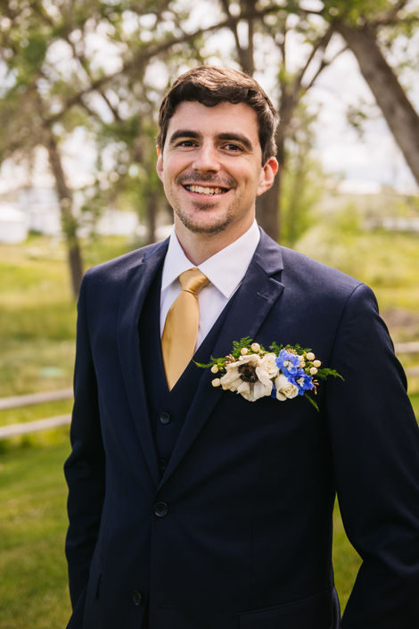 Groom wears a pocket square with white and pops of purple blooms