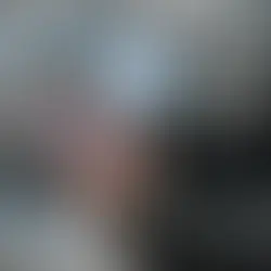 Person in suit uses a tablet outdoors with blue digital icons like gears and shipping symbols floating around, indicating tech focus.