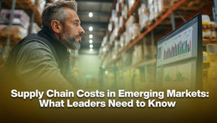 Man in a warehouse analyzes colorful graphs on a computer. Text: "Supply Chain Costs in Emerging Markets: What Leaders Need to Know."
