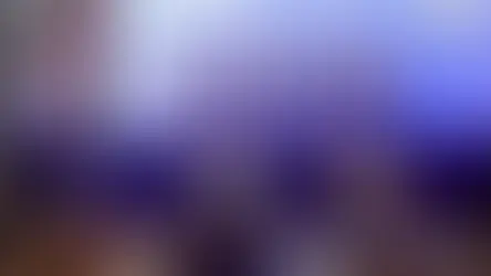 Panel discussion in a dimly lit room, four panelists speak on stage with a large screen behind them showing event details and portraits.