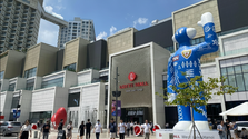 Visitors enjoy a sunny day at LOTTE Mall Hanoi, captured with striking sculptures and modern architecture in the backdrop.
