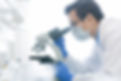 Young Chinese scientist or researcher in protective workwear studying new virus in microsc