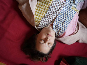 eine Frau liegt entspannt auf einer weichen Matte am Boden