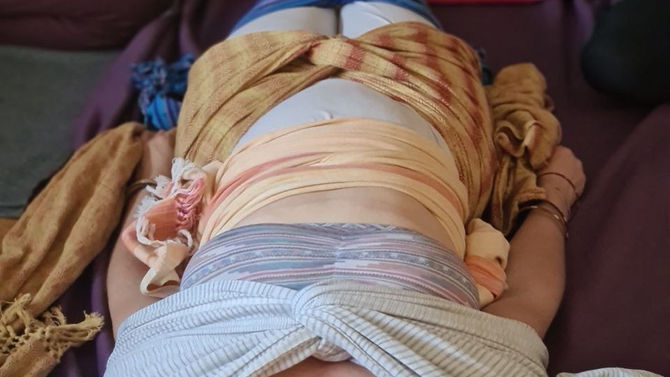 Eine Frau, die das Cierre de Matriz Ritual empfängt und eingehüllt in Tüchern auf dem Boden ruht.