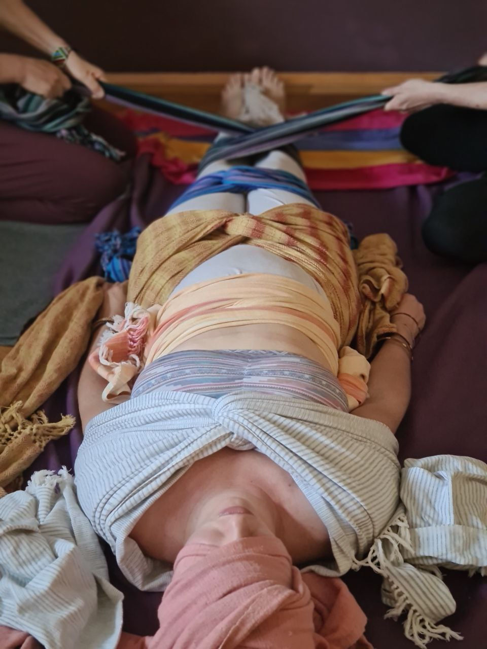 Eine Frau, die das Cierre de Matriz Ritual empfängt und eingehüllt in Tüchern auf dem Boden ruht.