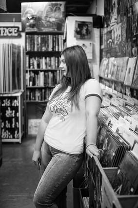 A black and white image of a girl posing in a record store in San Marcos, Tx during her senior photo shoot