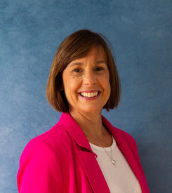 Smiling woman wearing a bright pink blazer during a Women's Empowerment studio portrait session.
