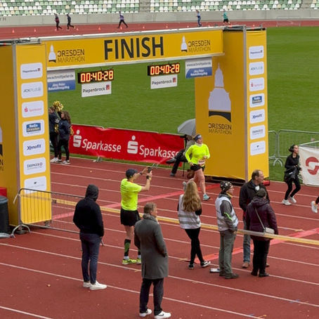Zieleinlauf beim Sparkassen-5-km-Lauf im Rahmen des Dresden Marathons 2025 in Dresden. Eine Läuferin überquert die Ziellinie im Stadion.
