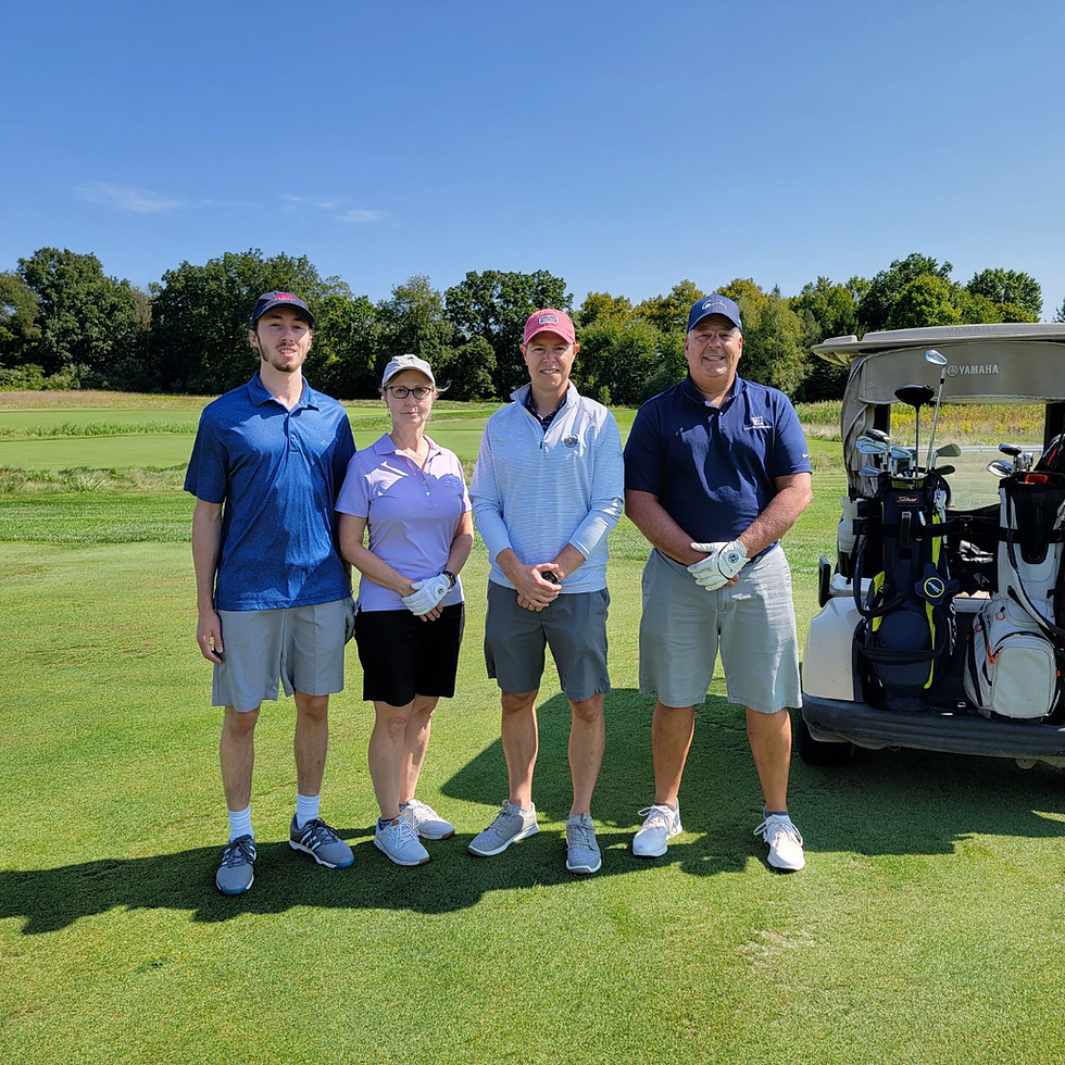 A family stands on a green golf course in front of a cart.
