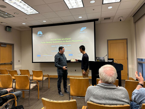 A young man stands in front of a projected presentation.
