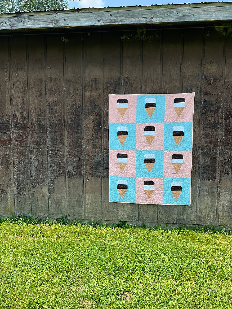 Thumbnail: full view of the throw size quilt pattern hanging on the side of a barn