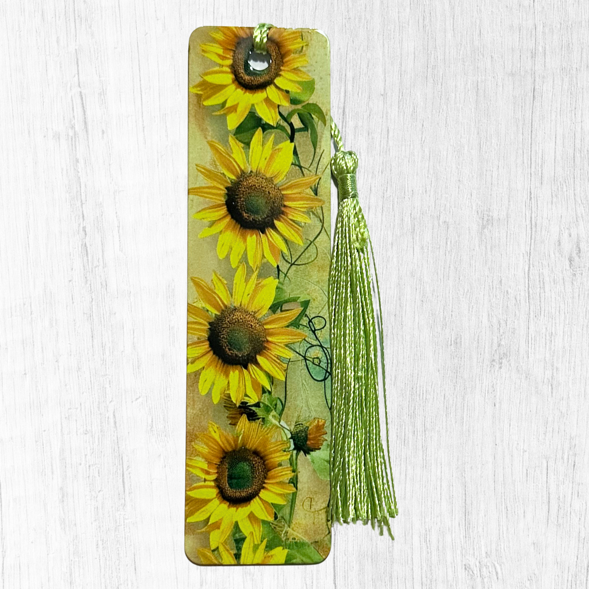Bookmark with bright yellow sunflowers on vintage style background with green tassel