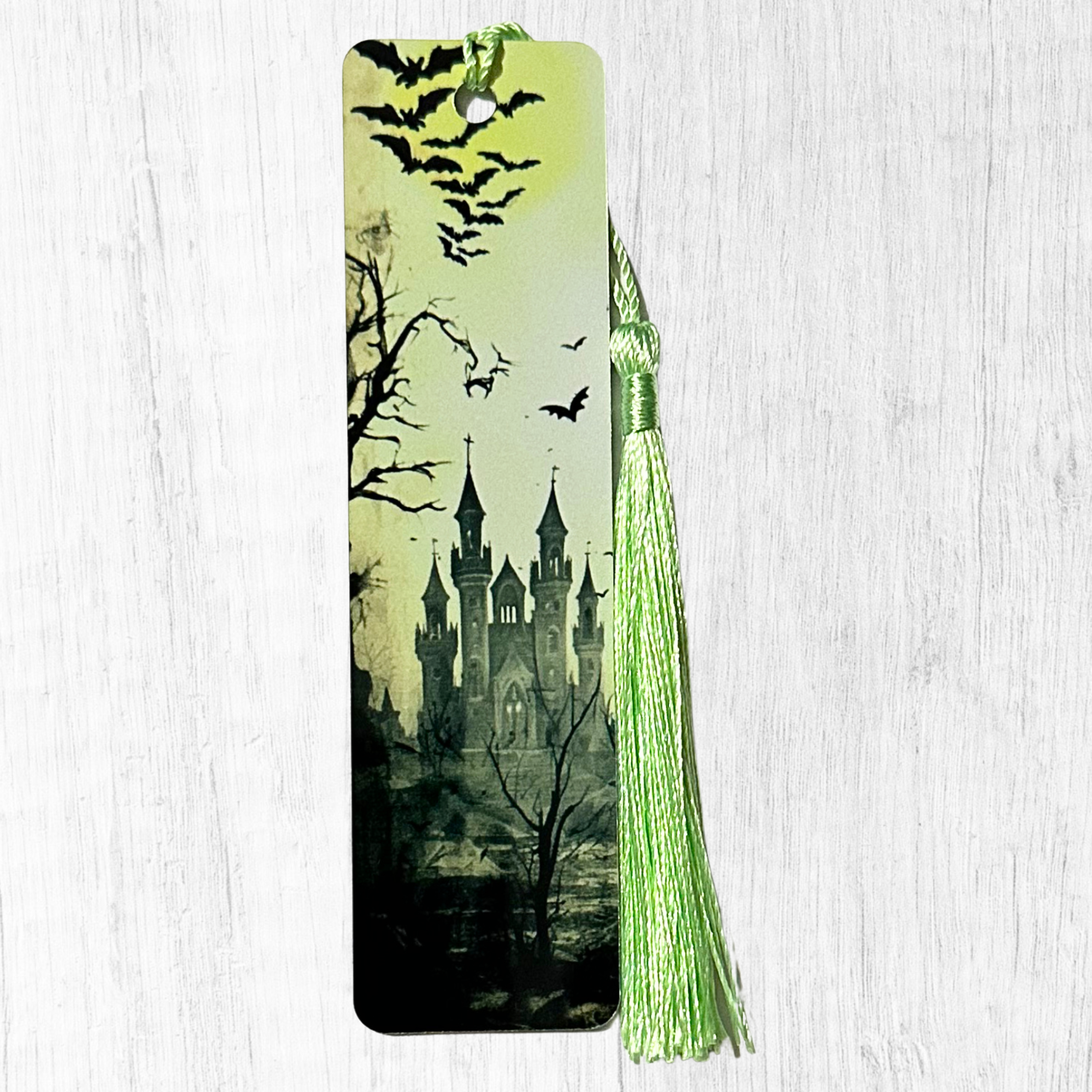 Green gothic castle bookmark with bats flying and eerie landscape with green tassel