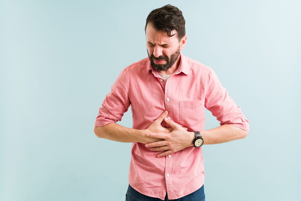 Indigestion concept. Attractive man in his 30s rubbing his abdomen because of a bad stomac