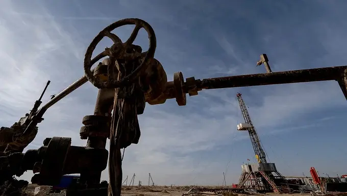 Oil edges down on easing Middle East risks but gains for a second month