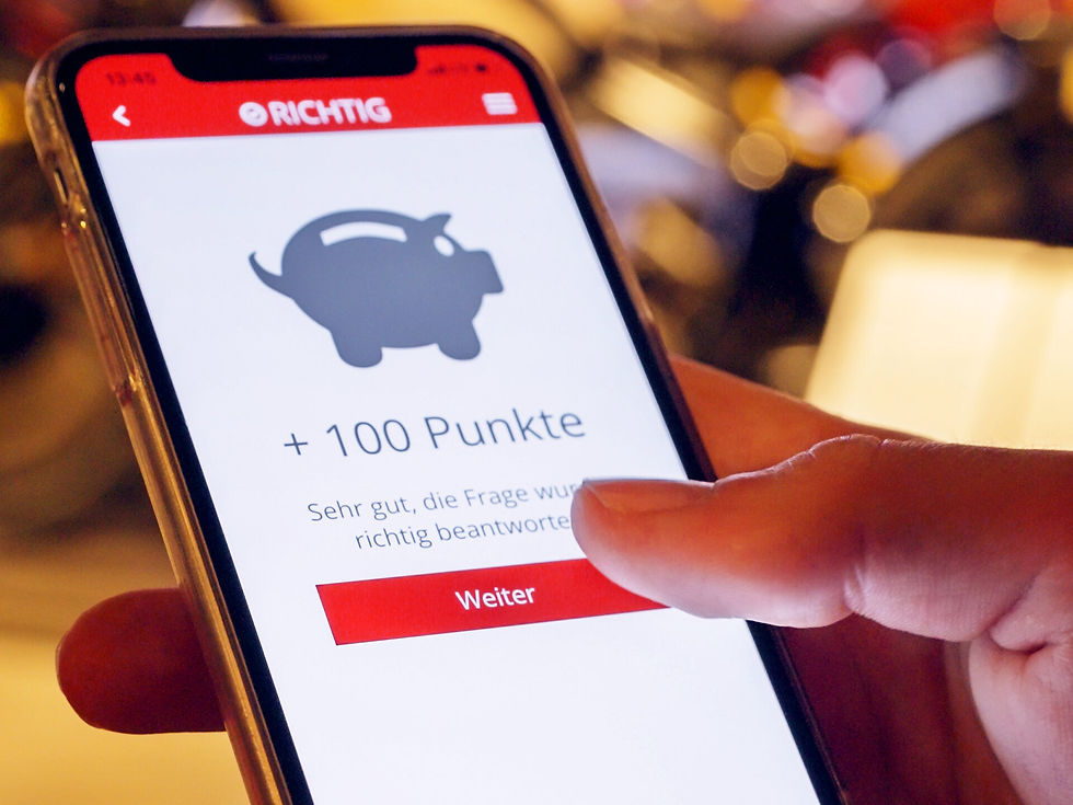 Smartphone zeigt Richtig-Bildschirm in App mit Sparschwein, +100 Punkte und Weiter; Finger tippt aufs Display.