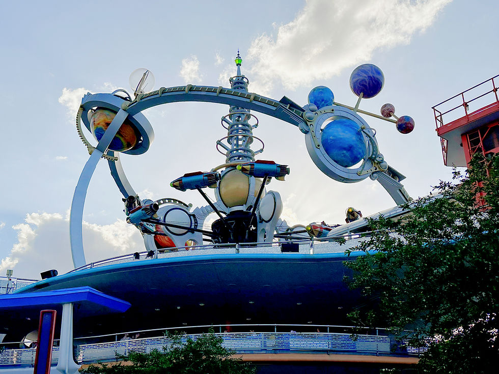 Astro Orbiter ride at Magic Kingdom with guests soaring in rocket ships around a spinning planetary structure, high above Tomorrowland with panoramic views of the park.