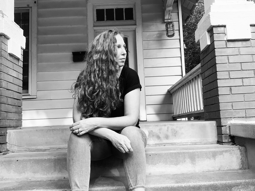 Portrait of artist Katie Adkins sitting on stairs, looking off camera