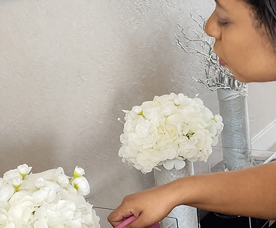 Event planner arranging a white floral centerpiece in a glass vase