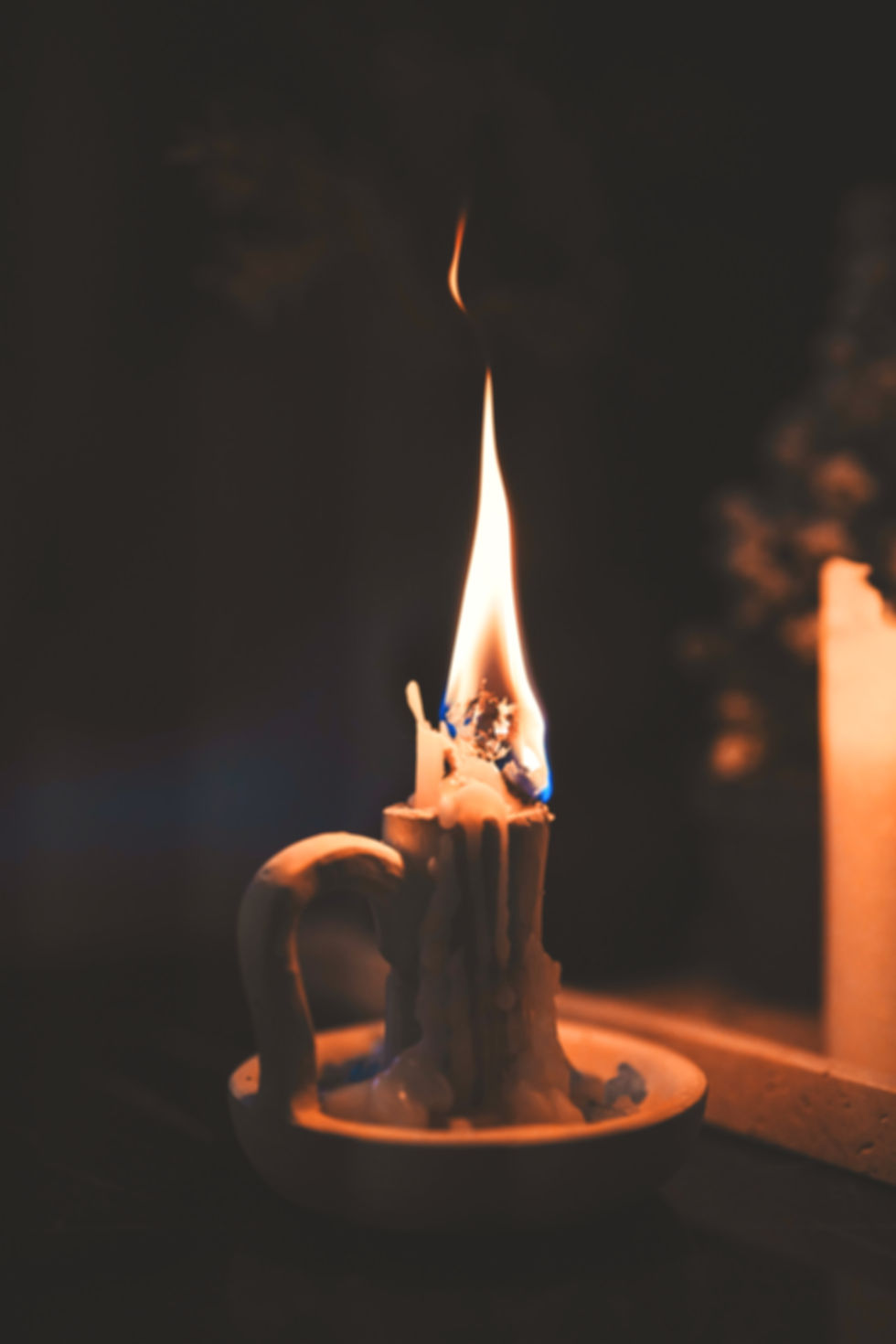 Bougie presque consumée avec une flamme haute, symbole de fatigue intérieure et de fin de cycle pendant l’hiver.