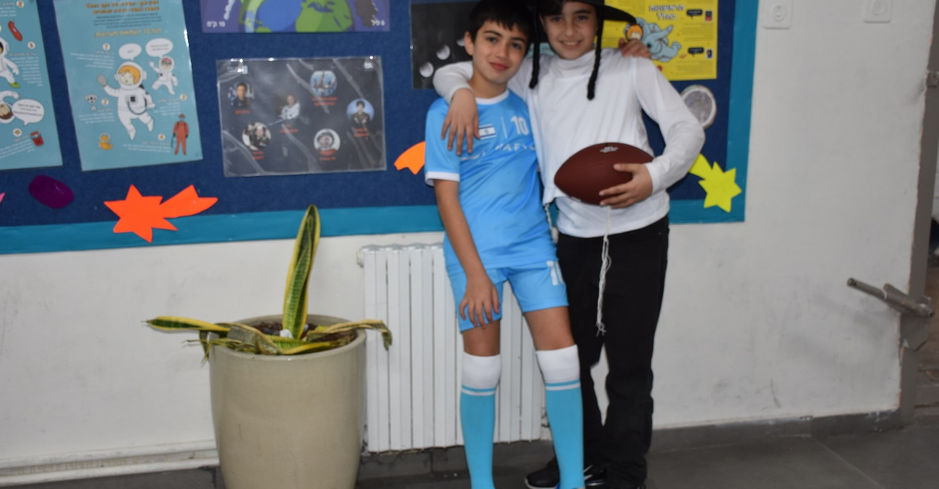 תלמידים בבגדי ספורט מחבקים כדור פוטבול