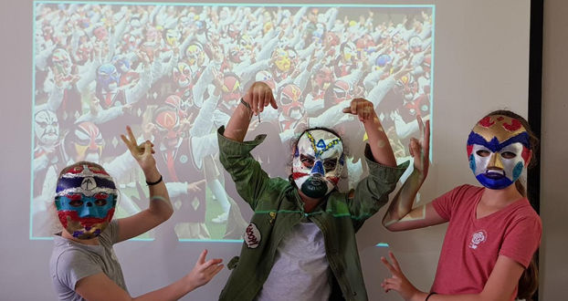 שלושה ילדים במסכות, ליד תמונה של קהל גדול