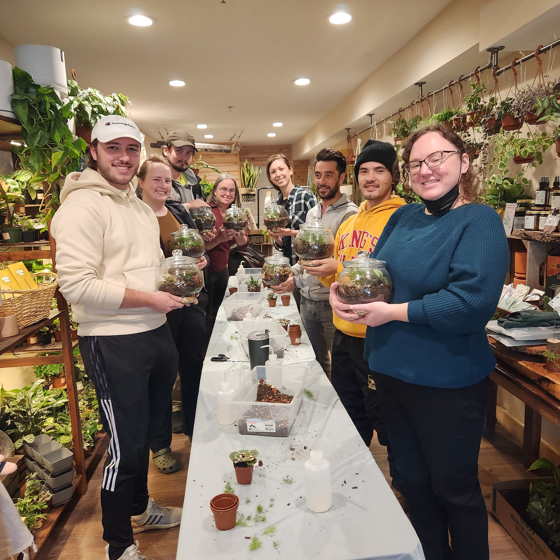 Staff with terrarium standing alongside a table in a cute plant shop