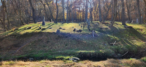 St Paul's Before, features an old cemetery on a green hillside with mature trees behind it, and an eroded stream bank in front of it. 