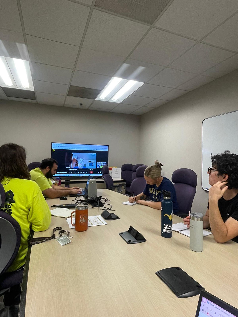 Interview with Ashley Traut from GBWC, crew sitting around a table in a conference room with Ashley on a screen