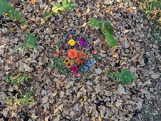Ostrich ferns and flowers. Ferns are added in a circle and memorial flower clippings lay in the center. Leaves are added as a mulch layer on top