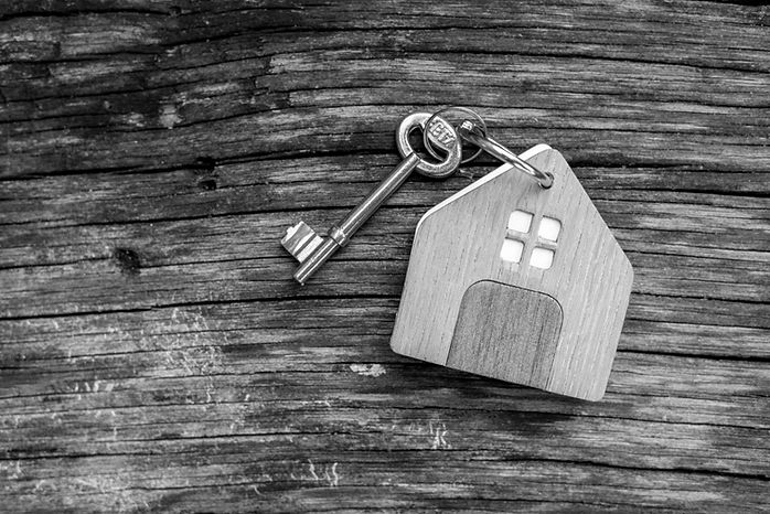 key with shaped house keychain on chain on wood texture background. Idea_ buying a house,