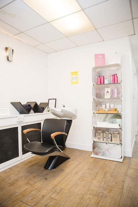 Salon chair with shelving alongside stacked with hair products