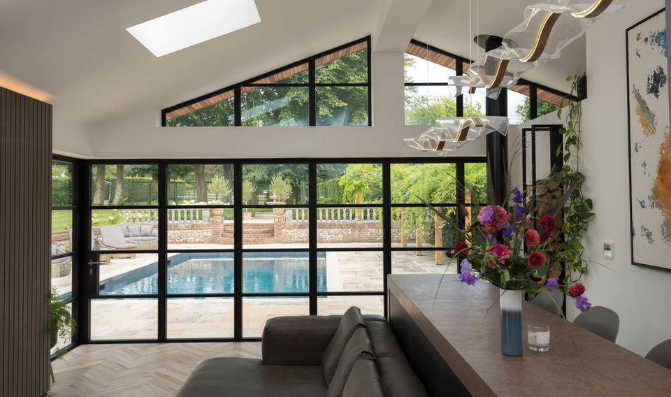 Origin bi-fold doors forming a glass wall in a living space with a view of a swimming pool