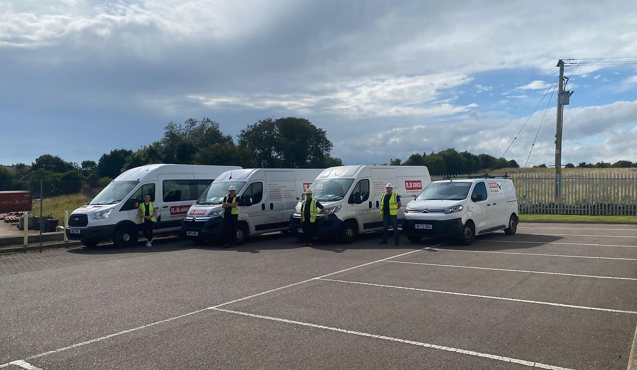 R & B Services team members stood next to 4 white different size vans