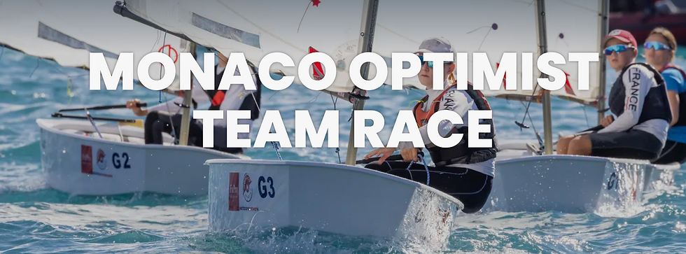 Three children racing in Optimist sailing boats.