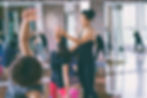 Yoga instructor adjusts student's pose during a class