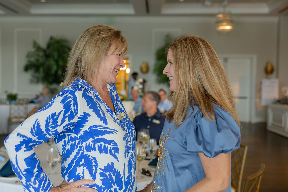 Carin warmly greets a guest at the celebration, both sharing a cheerful exchange.