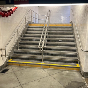 Subway station stairs, 'Exit Queens Blvd & Broadway' sign above.