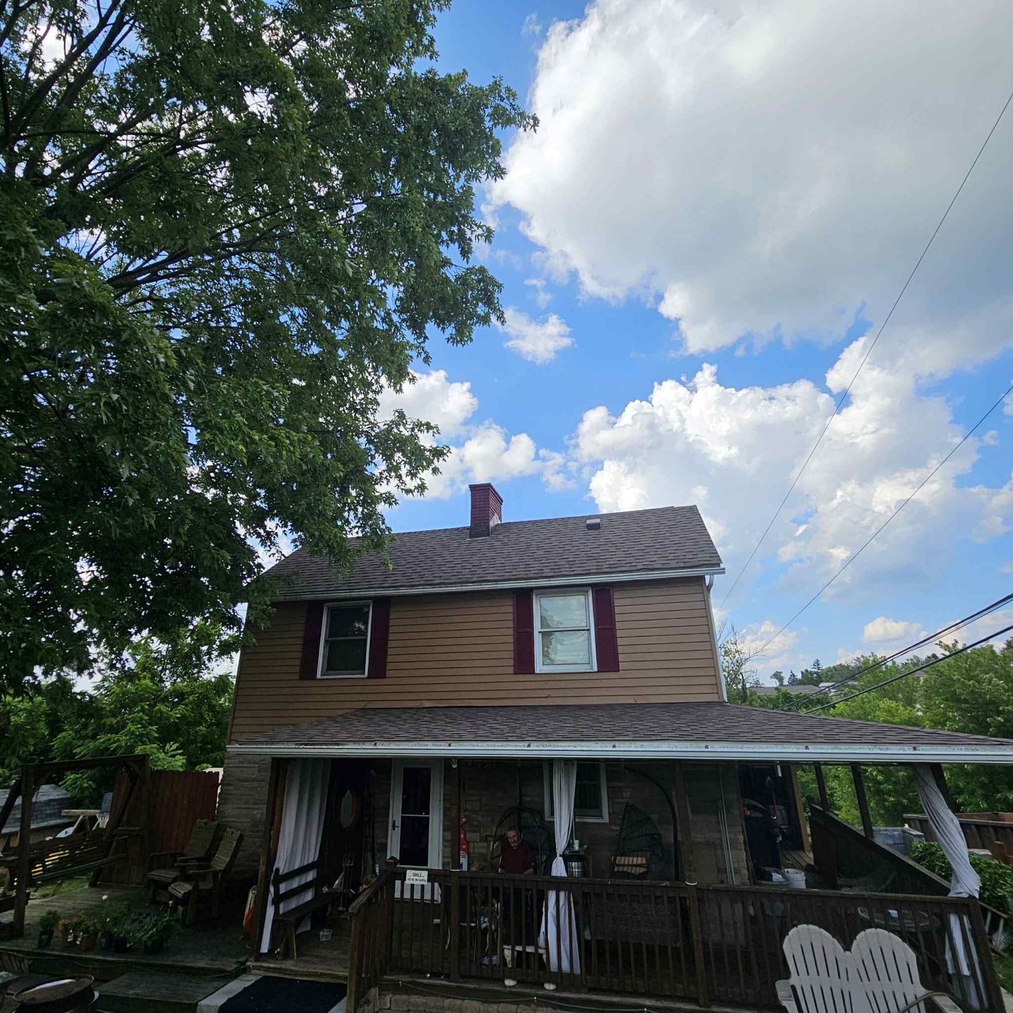 Two-story house with trees and a cloudy sky, All-Season Sunroom Conversion.