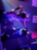 Two people stretching on yoga mats in purple light