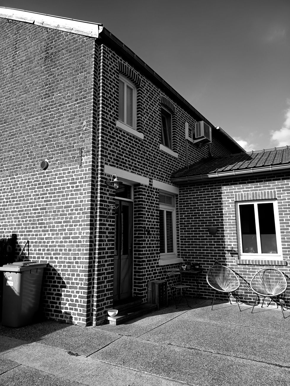 De bestaande woning is gesloten en introvert opgevat, met weinig relatie tot het achterliggende groen. Toch schuilt er in het perceel een bijzondere kwaliteit: een rustige, beschutte plek waar licht en tuin elkaar ontmoeten. De hof vormt een natuurlijk ankerpunt niet als decor, maar als leefruimte.
De uitdaging bestond erin een uitbreiding te ontwerpen die het huis opent naar deze plek, zonder het evenwicht en de schaal van de oorspronkelijke woning te verstoren.
