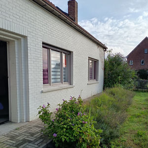 voorgevel van een éénsgezinswoninguit 1904 met wit geverfde bakstenen en paarskleurig glas-in lood