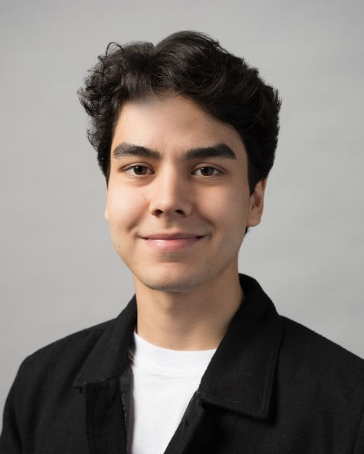 young professional male standing against a white wall.