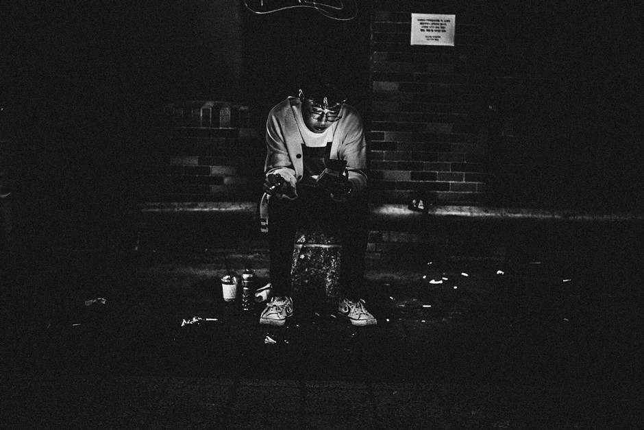 young man illuminated by phone light on dark street