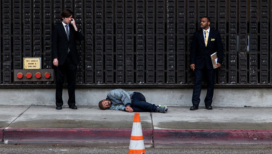 sleeping homeless man with two men in suits on each side