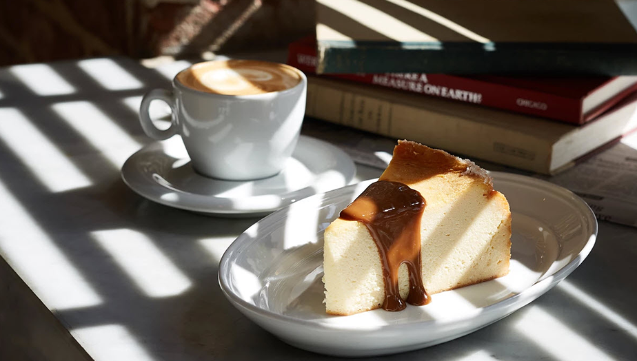 latte and cheesecake served on a table with books