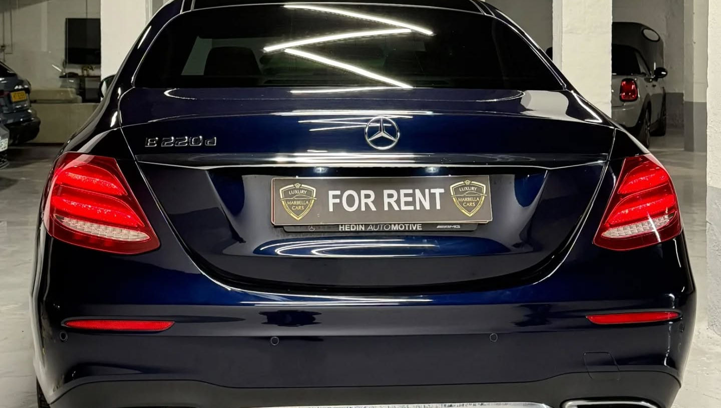 Straight rear view of blue metallic Mercedes E220d featuring slim LED taillights, subtle boot lid spoiler and clean rear bumper, premium sedan hire Marbella