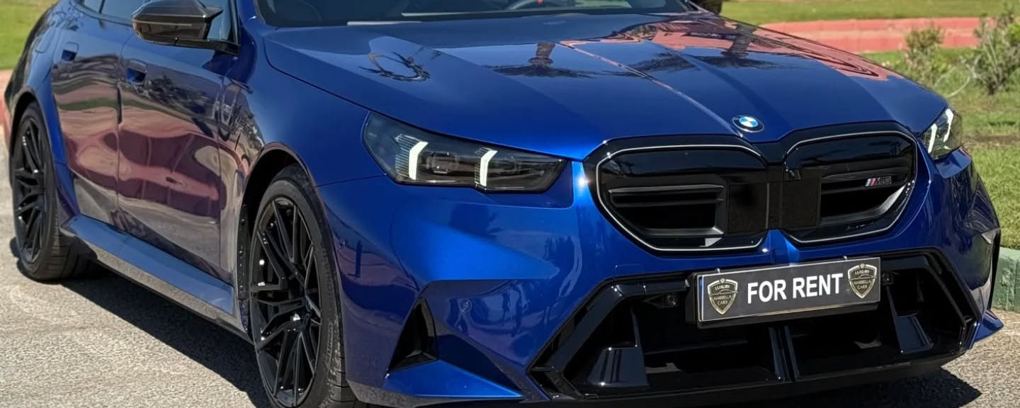 Commanding front-right three-quarter hero angle featuring massive air intakes, slim LED headlamps and M fender vents on BMW M5 Competition sedan, Marbella rental
