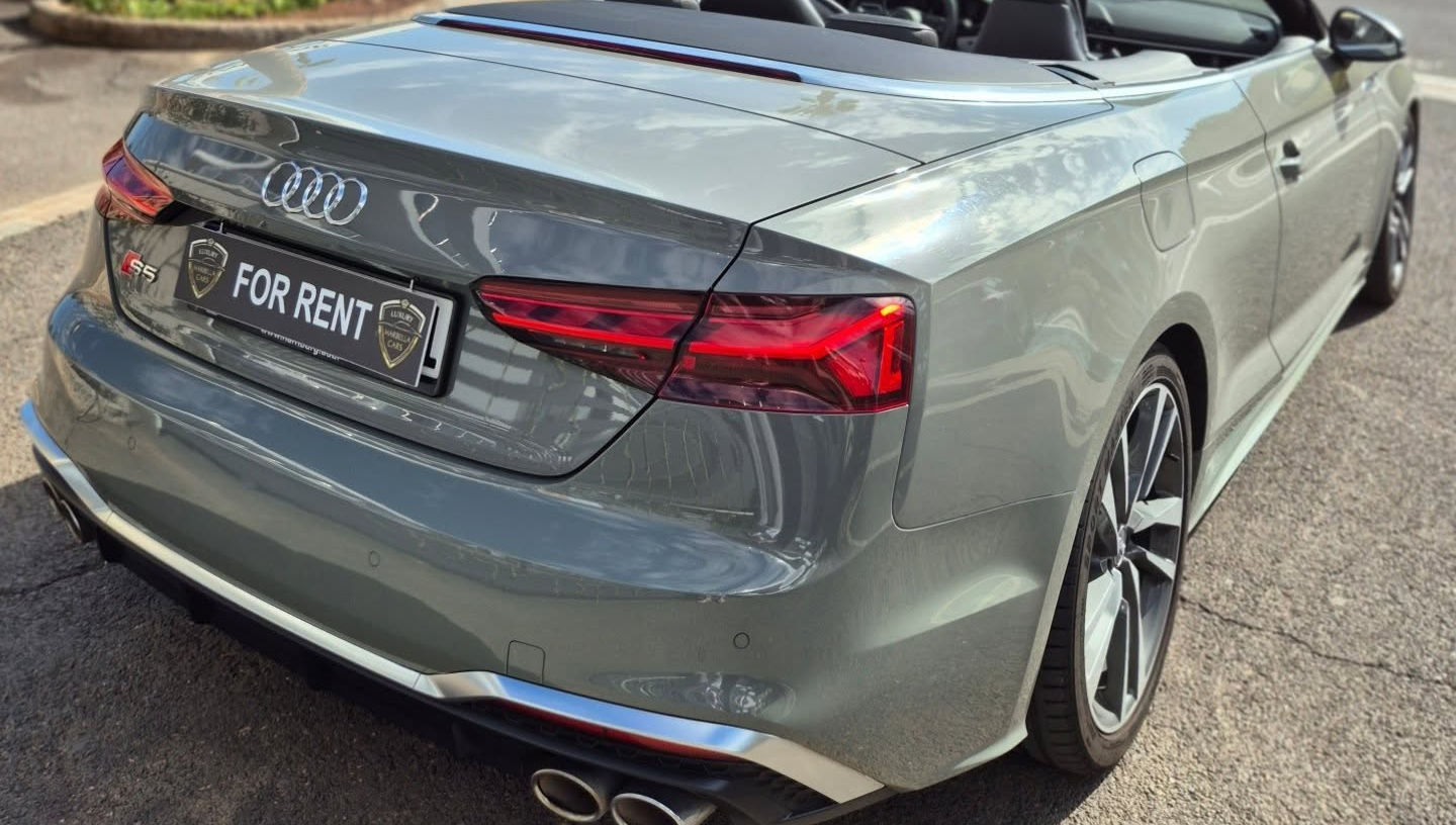 Dramatic rear-right corner view highlighting fabric soft top compartment, quad exhausts and diffuser on Audi S5 Cabriolet, Marbella rental