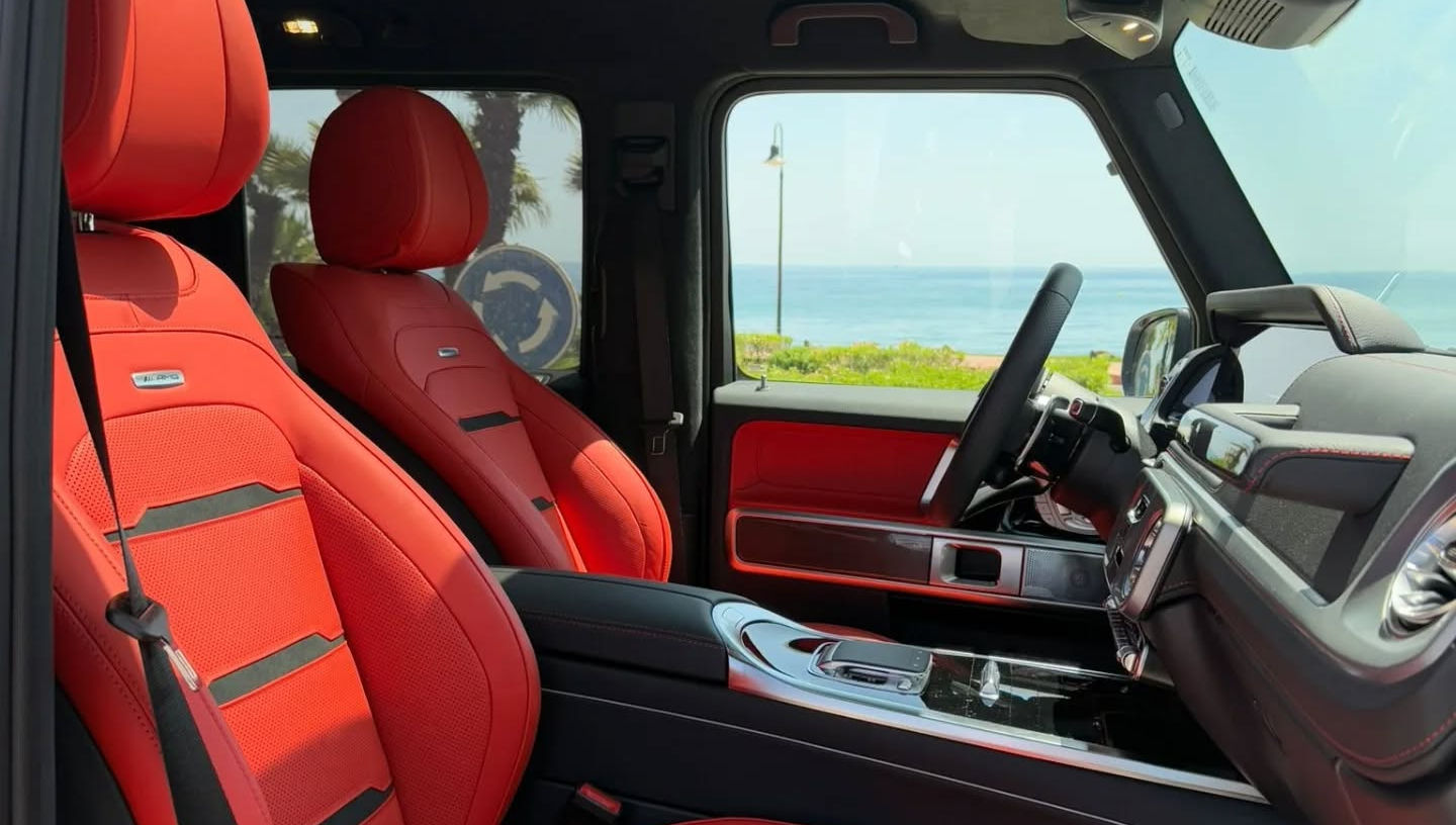 Front seats of Mercedes G63 AMG 577 hp with leather upholstery, integrated headrests and wide centre armrest for luxury comfort.